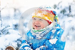 Baby playing with snow in winter. Child in snowy park.