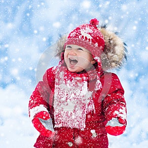 Baby playing with snow in winter.