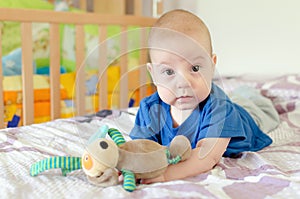 baby playing with soft toy on the bed