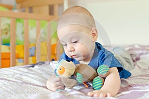 Baby playing with soft toy on the bed