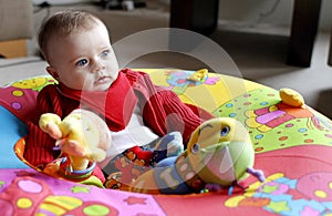 Baby playing with soft toy in playpen