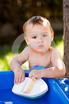 Baby playing with toy boat in water outdoors