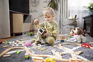 Baby playing with toy railroad, trains and cars on the floor