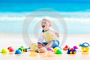 Baby playing on tropical beach digging in sand