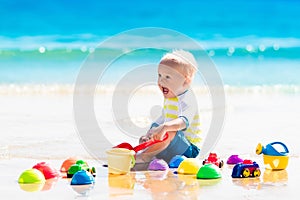 Baby playing on tropical beach digging in sand