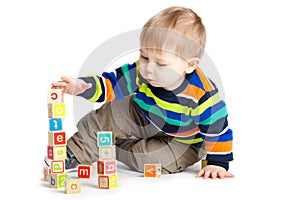 Baby playing with wooden toy cubes with letters.