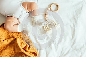 Baby playing with a wooden toy on white linens