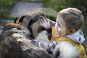 The baby plays with the animal in nature.