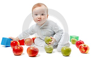 Baby plays with apples and toys. Studio Portrait, isolated on a white background
