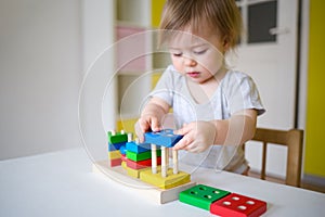 Baby plays in the constructor. small child puts the rings on the pins. concept of development of fine motor skills