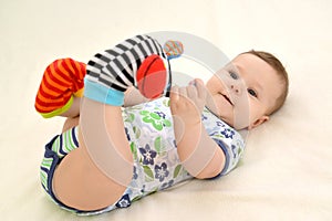 The baby plays legs in color socks with rattles