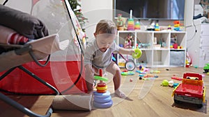 Baby plays with pyramid toy. Happy family a kid dream concept. Baby plays pyramid with mugs in the playroom at home