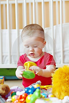 Baby plays rattle against white bed