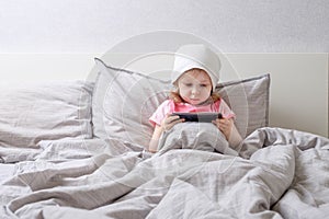 Baby plays smartphone on the bed