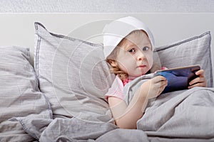 Baby plays smartphone on the bed