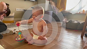 baby plays spinning top toy. happy family kid dream concept. baby in a diaper is learning to spin a spinning top toy on