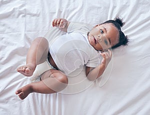 Baby, portrait and girl on a bedroom bed feeling relax and calm in a nursery after rest. Young newborn, child and kid