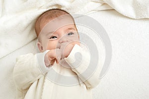 Baby portrait lie on white towel in bed, yellow toned