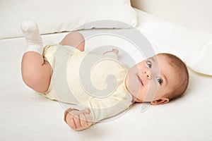 Baby portrait lie on white towel in bed, yellow toned