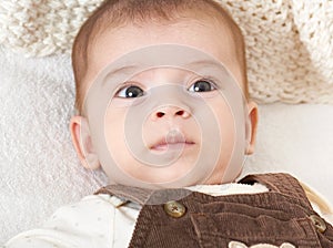 Baby portrait lie on white towel in bed, yellow toned