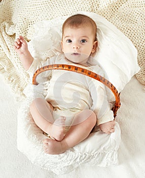 Baby portrait lie on white towel in bed, yellow toned