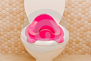 Baby potty and baby pink toilet seat in toilet. Hygiene. Children`s toilet. Children`s pad, cover, toilet seat. The child goes to