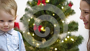 Baby and pregnan mom hang red ball toy on Christmas tree. happy childhood concept. child and mother decorate tree with