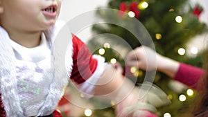 Baby and pregnan mom hang red ball toy on Christmas tree. happy childhood concept. child and mother decorate tree with