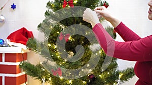 Baby and pregnan mom hang red ball toy on Christmas tree. happy childhood concept. child and mother decorate tree with