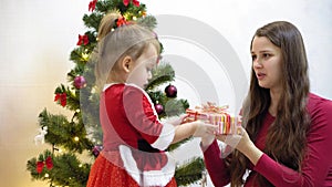 Baby and pregnan mom hang red ball toy on Christmas tree. happy childhood concept. child and mother decorate tree with
