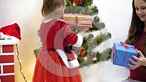 Baby and pregnan mom hang red ball toy on Christmas tree. happy childhood concept. child and mother decorate tree with