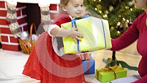 Baby and pregnan mom hang red ball toy on Christmas tree. happy childhood concept. child and mother decorate tree with