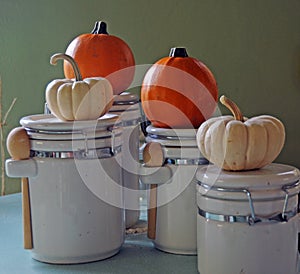 Baby pumpkins on white canisters