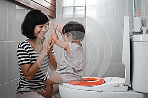 baby pup clapping jokingly with his mother against the background of the toilet