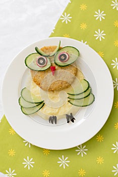 Baby puree in the shape of an owl. Mashed potatoes. Children`s menu on a green background.
