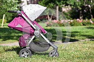 Baby pushchair with summer kit is on green meadow in summer sunny park, side view, infant perambulator series