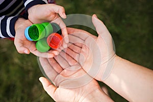 Baby puts plastic lids in mother`s hands. parent and his child collect cover. e.