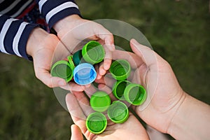 Baby puts plastic lids in mother`s hands. parent and his child collect cover. recyclable.