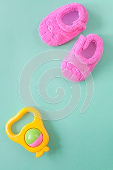 Baby rattle and booties on green background