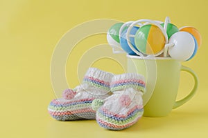 Baby rattle and booties on yellow background