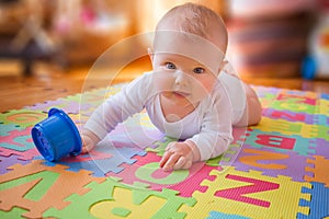 Baby reaching cup on alphabet mat