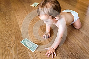 Baby reaching some dollar bills, wasted family savings concept