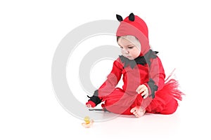 Baby with a red demon disguise watching a pacifier