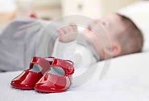 Baby red shoes and babe lying on the background