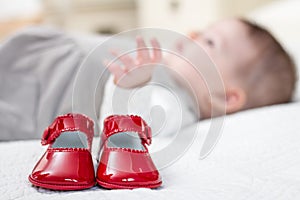 Baby red shoes and babe lying on the background