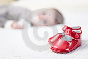 Baby red shoes and babe lying on the background