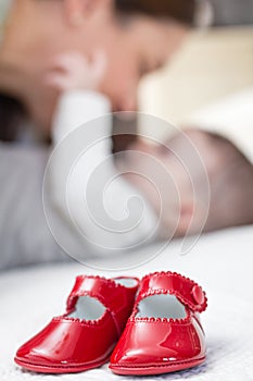 Baby red shoes pair and babe on the background