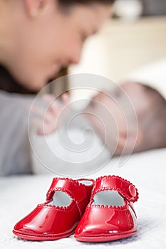 Baby red shoes pair and babe on the background