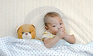 baby relaxing in bed with his finger in mouth