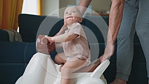 baby rides a motor scooter indoors. dad rides his son teaches him to ride a scooter around the room at home. happy